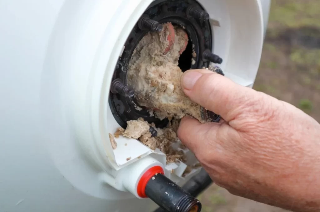 Plumber inspecting sediment buildup inside a water heater tank to diagnose popping and rumbling noises at NWA C&S Plumbing.