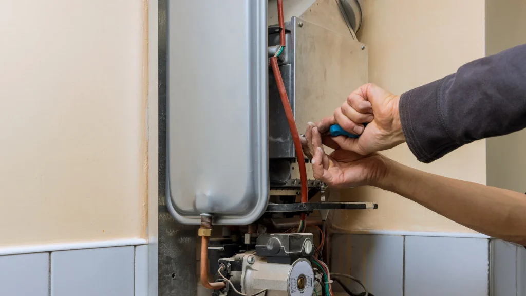 A plumber using a screwdriver to repair the internal components of a tankless water heater, representing Fix Your Pipes' professional water heater repair and replacement services in Fayetteville AR