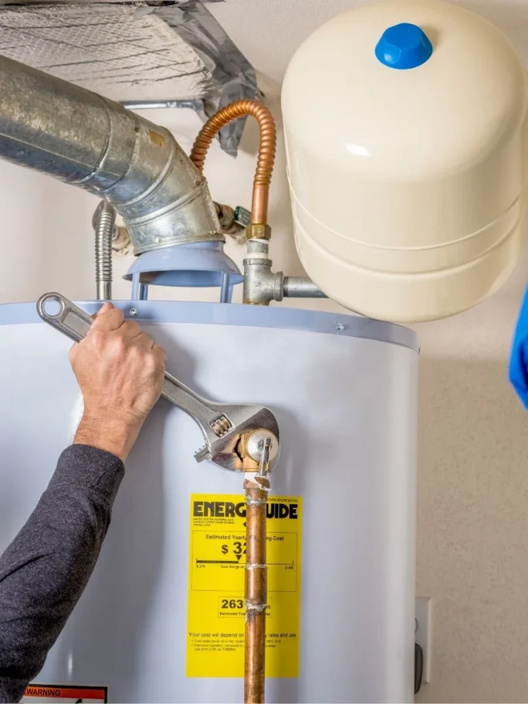 Plumber using a wrench to repair a residential water heater with expansion tank