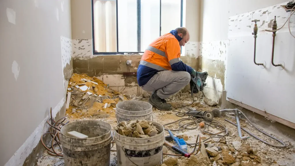 Plumber planning drain and water line installation during a bathroom remodel