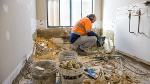 Plumber planning drain and water line installation during a bathroom remodel